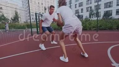 慢动作。 年轻的男女<strong>篮球</strong>运动员在城市景观操场上<strong>运球</strong>。 人控制着他的球